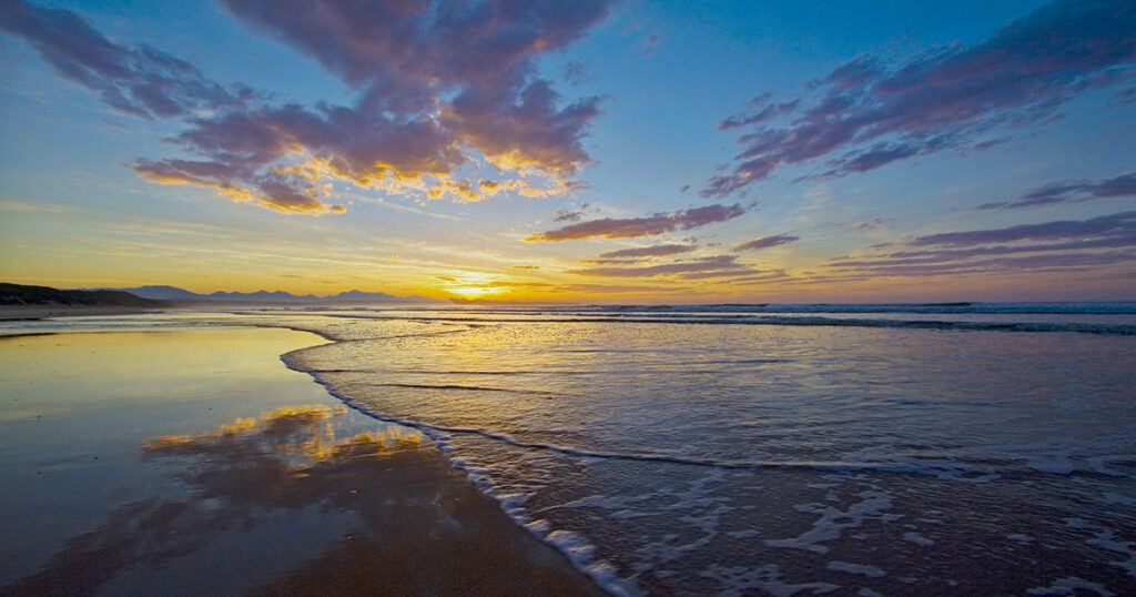 De Bakke Beach at low tide, the sun rising gently in the East.
